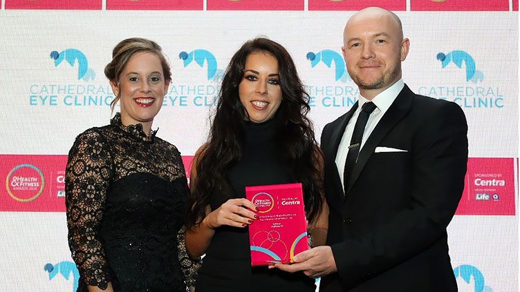 Gary McArdle of category sponsor Cathedral Eye Clinic presents HR's Sarah Montgomery and Danielle Fletcher from Allstate NI with the trophy for Best Corporate Wellness Programme. 