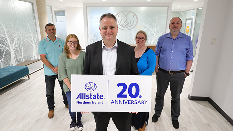 John Healy holding a ANI 20th anniversary sign with ANI employees behind him. 