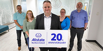 Allstate NI employees holding a 20th anniversary sign. 